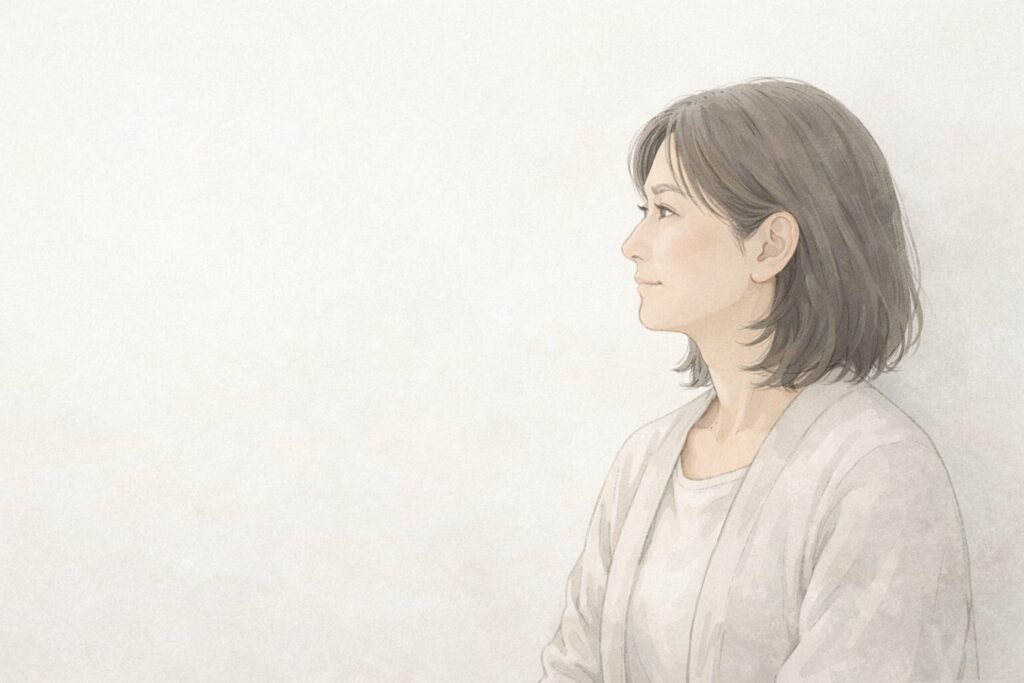 高齢の母との関係を振り返りながら、少し気持ちが整理されつつある50代後半女性が静かに遠くを見つめている様子